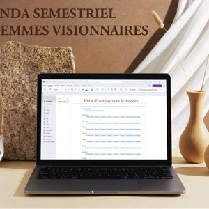 Peut inclure: Un ordinateur portable affichant un document intitulé "Plan d'action vers le succès" avec une liste d'éléments d'action. L'ordinateur portable est sur une surface brun clair avec un vase de fleurs séchées et un vase plus petit à droite.