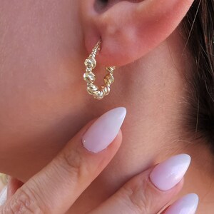 May include: Gold hoop earrings with a textured, beaded design.