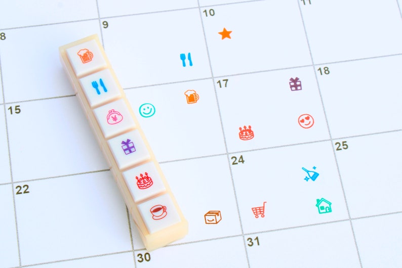 May include: A white calendar with a row of colorful icons on a white bar. The icons include a beer mug, a fork and knife, a purse, a gift box, a birthday cake, and a coffee cup. The calendar has numbers 8, 9, 10, 11, 15, 17, 18, 22, 24, 25, 30, and 31.