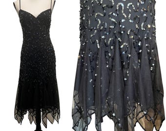 May include: Black evening dress with spaghetti straps and a sweetheart neckline. The dress is embellished with sequins and has a flared, asymmetrical hemline. The dress is displayed on a mannequin.