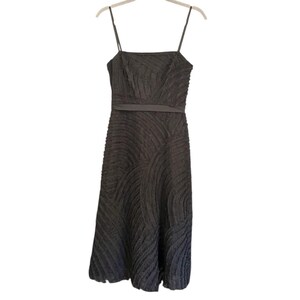 May include: A dark gray midi dress with thin spaghetti straps. The dress features a textured, patterned design and a thin belt at the waist. The dress is hanging on a hanger against a white background.