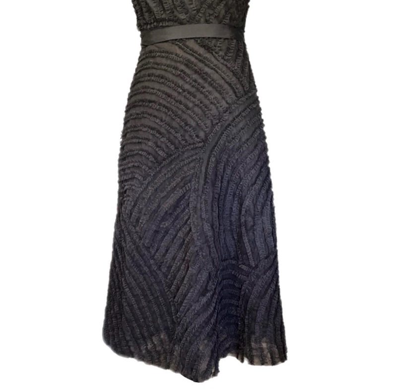 May include: A dark gray dress with a textured, ribbed design. The dress features a fitted bodice, a thin belt at the waist, and a flared skirt. The fabric has a unique, layered appearance.