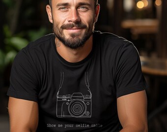 May include: Black t-shirt with a white line drawing of a camera and the text "Show me your selfie smile." The shirt is made of a soft material and has short sleeves.