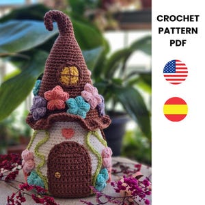 Puede incluir: Una casa de gnomo de ganchillo hecha a mano con un tejado puntiagudo marrón, adornada con coloridos detalles florales. La casa presenta una puerta marrón, una ventana amarilla y un detalle en forma de corazón. Se muestra el texto "CROCHET PATTERN PDF".