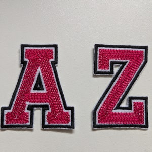 May include: Two felt letter patches, one "A" and one "Z", in a bright pink color with white outlines and black stitching.