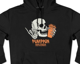 Puede incluir: Sudadera con capucha negra con un gráfico de calavera blanca sosteniendo una taza de café naranja y haciendo un gesto con la mano. El texto "PUMPKIN SEASON" está impreso en naranja debajo. La sudadera tiene una capucha con cordón y un bolsillo delantero.