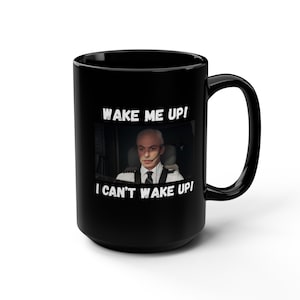 Pode incluir: Caneca de cerâmica preta com a frase branca "WAKE ME UP! I CAN'T WAKE UP!". O design apresenta um homem com uniforme de piloto. A caneca tem uma alça grande e é adequada para bebidas quentes.