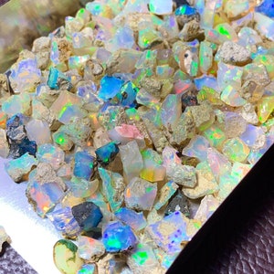 May include: A collection of rough opal gemstones in various sizes and shapes. The opals are a mix of white, grey, and iridescent colours.