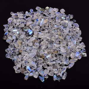 May include: A large pile of iridescent white moonstone chips. The chips are various sizes and shapes, with a shimmering blue and green sheen.
