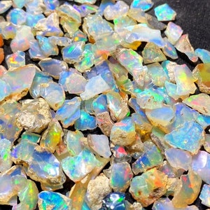 May include: A collection of iridescent opal chips in various sizes and shapes. The chips are a mix of white, blue, green, and yellow.