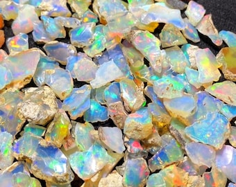 May include: A collection of iridescent opal chips in various sizes and shapes. The chips are a mix of white, blue, green, and yellow.