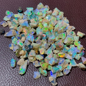 May include: A pile of rough, iridescent opal gemstones in various sizes and shapes. The opals are a mix of white, blue, green, and yellow.