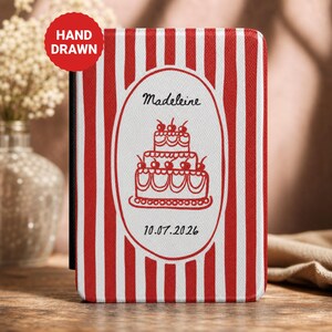 May include: A rectangular protective case featuring a red and white vertical striped pattern. A central white oval contains a hand-drawn red illustration of a three-tiered cake with cherries, the name Madeleine, and the date 10.07.2026 in black text.