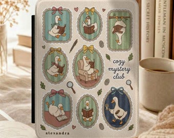 Może przedstawiać: Kremowe etui na czytnik e-booków z wzorem kaczek w ozdobnych ramkach czytających książki. Na froncie nadrukowano tekst "cozy mystery club" oraz "alexandra". Projekt zawiera małe ilustracje pióra, lupy i liści.
