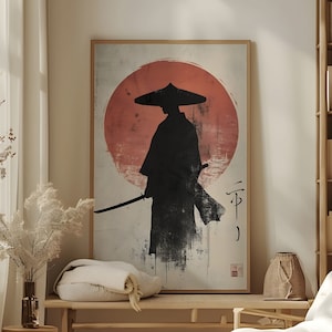 May include: A minimalist black and white illustration of a samurai warrior standing in front of a red sun. The image is framed and hanging on a wall in a room with a wooden bench and a white armchair.