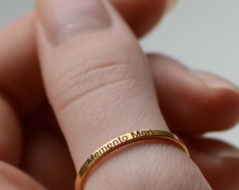 May include: A gold ring with the inscription "Memento Mori" on the band.