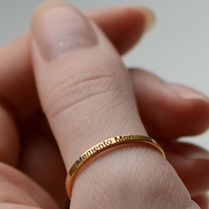 Puede incluir: Un anillo de oro con la inscripción "Memento Mori" en la banda.