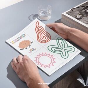 Puede incluir: Un juego de cuatro tarjetas de trazado con los dedos para calmarse, con ilustraciones coloridas de un cerebro, una pera, un sol y una mariposa. Las tarjetas est&aacute;n impresas en papel blanco y tienen el texto "Finger Tracing Calming Cards" y "Calm Retreat".