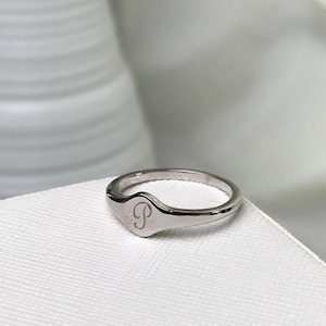 May include: A silver signet ring with a letter "P" engraved on the top.
