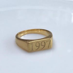 Op de afbeelding: Een gouden zegelring met het jaar 1997 gegraveerd op de bovenkant.