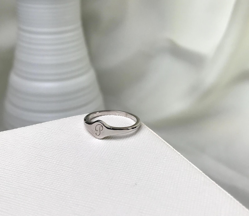 May include: A silver signet ring with a letter "P" engraved on the top.