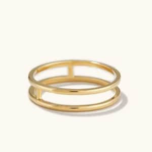 Puede incluir: Un anillo de doble banda de color dorado con un diseño minimalista.