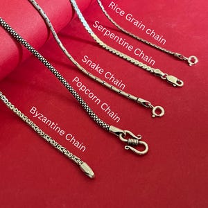 May include: Five silver-toned metal chains labelled as Rice Grain chain, Serpentine Chain, Snake Chain, Popcorn Chain, and Byzantine Chain. Each chain features a distinct link pattern and a metal clasp, displayed against a solid red background.