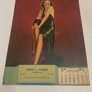 May include: Vintage 1941 calendar featuring a glamorous woman in a black dress with a high slit, posing against a red backdrop. The calendar includes the month of January and the name "Fred L. Ward, Lumberman" at the bottom.