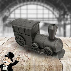 May include: A black toy train engine with a chimney and wheels. The train is made of wood and has a rustic look.
