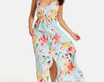 May include: A light blue halter dress with a floral pattern featuring pink, orange, and yellow roses. The dress has a slit and is paired with nude heels. The dress has a cinched waist and a flowing skirt.
