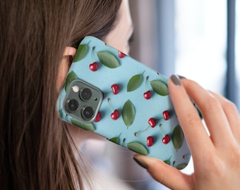 以下が含まれることがあります： 赤いチェリーと緑の葉の模様がついた青い携帯電話ケース