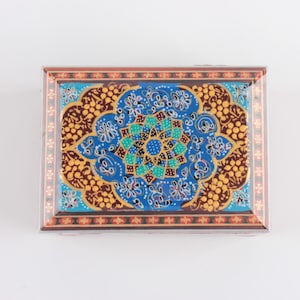 May include: A rectangular decorative box featuring a vibrant blue central medallion with a geometric floral pattern in turquoise, white, and gold. The surrounding border displays a brown and gold dotted motif, framed by a thin red and gold edge.