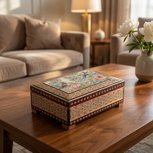 May include: A rectangular wooden box featuring a lid with a painted floral and bird motif in shades of blue, pink, and green. The sides of the box are decorated with intricate geometric patterns in brown and gold tones, supported by four small feet.