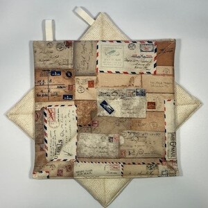 May include: A pair of beige and white pot holders with a square shape. The front of the pot holder features a vintage design of postage stamps with red, blue, and black accents. The back of the pot holder is a solid beige color with a subtle pattern.