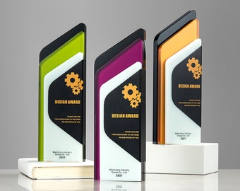 Puede incluir: Tres trofeos de diseño de acrílico negro, blanco y dorado con un diseño de engranaje. El texto "DESIGN AWARD" está en cada trofeo. El texto "THANK YOU FOR YOUR DEDICATION TO THE TEAM WE ARE PROUD OF YOU" está en cada trofeo. El texto "Machinery Industry Group Co. Ltd 2021" está en cada trofeo.