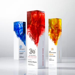 May include: Three rectangular awards with white bases and colorful resin tops. The left award has blue resin and text for Nova Security. The center award has red resin and text for Emma Hayes. The right award has yellow resin and text for BrightCore Ltd.