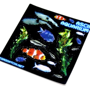 以下が含まれることがあります： ピクセル化された魚や海藻などの水生生物が描かれた黒いステッカー。「ASCII AQUARIUM」の文字が青色で、「TOMOATCHI.NET」の文字が白色で表示されています。オレンジ、白、青、緑の要素がデザインに取り入れられています。