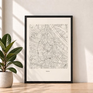 Könnte beinhalten: Ein gerahmter Wandkunstdruck mit einem detaillierten schwarz-weißen Stadtplan von Wien. Die Karte zeigt ein komplexes Straßennetz und den städtischen Grundriss auf einem hellcremefarbenen Hintergrund, mit dem Wort Vienna unten mittig.