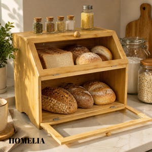 May include: A wooden bread bin with a glass door, containing different types of bread. The top shelf has sliced bread and rolls, and the bottom shelf has whole loaves. Small glass jars of spices are on top. The word "HOMELIA" is visible.