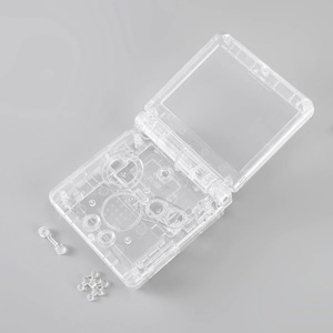 May include: A clear plastic shell for a handheld gaming device. The shell is open and shows the buttons and controls. The shell is made of clear plastic and has a smooth finish.