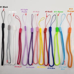 May include: A collection of colorful wrist straps in various shades, including black, grey, white, red, purple, pink, yellow, blue, green, and orange. Each strap has a loop and a rectangular plastic piece. The image includes text labels for each color.