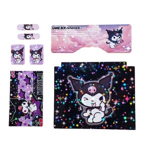 Könnte beinhalten: Eine Game Boy Advance SP Konsolenhaut mit einem schwarz-weißen Kuromi-Charakter mit einer rosa Schleife und einem Totenkopf auf dem Kopf. Der Hintergrund ist ein schwarzer und violetter Sternenhimmel mit einem holografischen Effekt. Die Haut enthält eine Aufkleberfolie mit zusätzlichen Kuromi-Charakteren und Sternen.