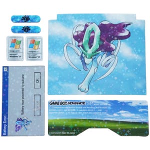 Könnte beinhalten: Eine Game Boy Advance SP Konsole mit einem blauen und weißen Aufkleber, der ein Pokémon-Charakter zeigt. Der Aufkleber hat einen blauen Hintergrund mit weißen Sternen und einer hellblauen Wolke. Das Pokémon-Charakter ist eine hellblaue und violette Kreatur mit einem grünen Edelstein auf dem Kopf. Der Aufkleber enthält auch den Text "GAME BOY ADVANCE SP" und "MODEL NO. AGS-101".