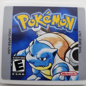 May include: A blue and brown Pokemon game cartridge with the text "Pokemon" in yellow letters and "TM" in black letters. The game is rated "E" for Everyone by the ESRB. The text "DMG-APEE-USA" and "THIS SIDE OUT" are printed on the sides of the cartridge.