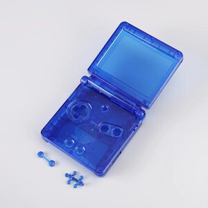 May include: A disassembled blue Game Boy Advance SP console with the top screen open and the bottom screen, buttons, and other components visible. The console is on a white surface.