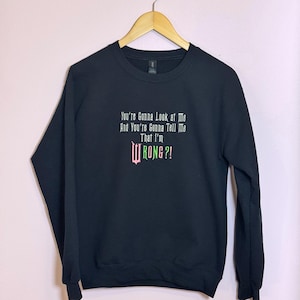 May include: Black sweatshirt with a white graphic print that says "You're gonna look at me and you're gonna tell me that I'm WRONG?" The text is in a green and pink font.