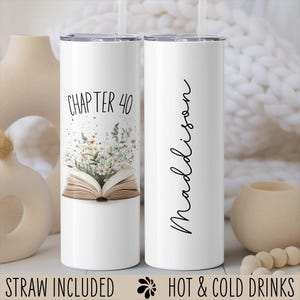 May include: Two white stainless steel tumblers with a straw. One tumbler has the text "Chapter 40" and a floral design with an open book. The other tumbler has the name "Madison" written vertically.