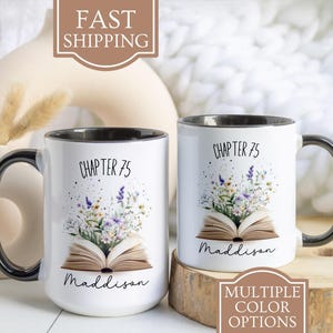 May include: Two white ceramic mugs with black handles. Both mugs feature a floral design with an open book and the text "Chapter 75" and "Maddison".