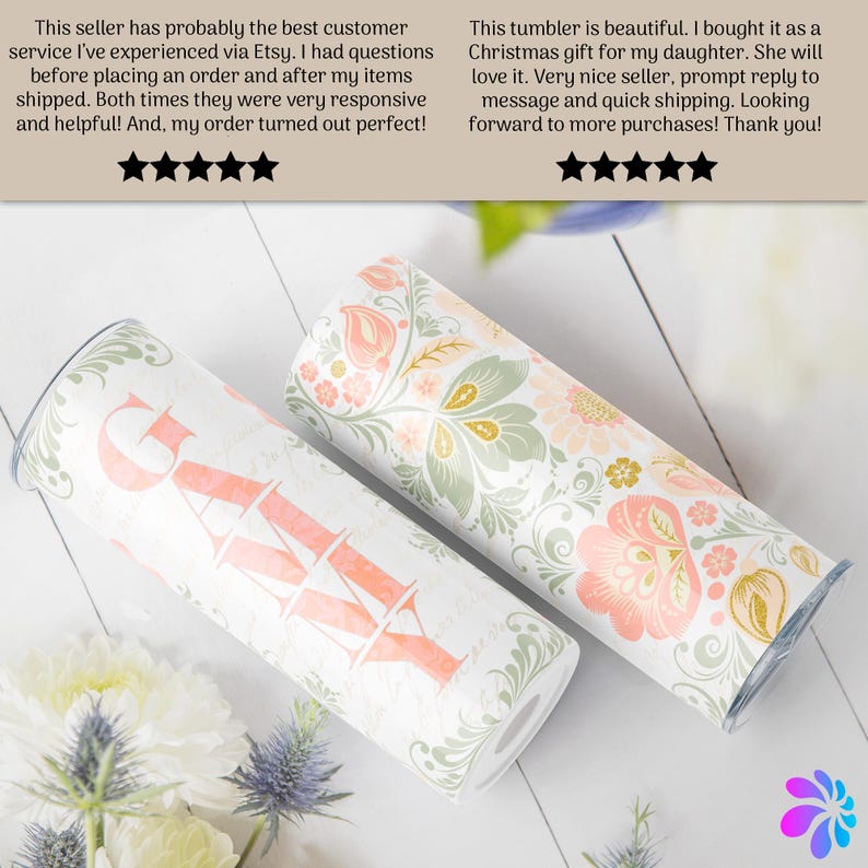 May include: Two stainless steel tumblers with a floral pattern. One tumbler has the word "Grateful" written in pink on the front. The tumblers are on a white wooden surface.