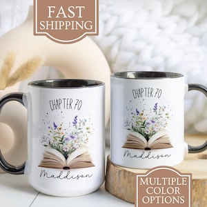 May include: Two white ceramic mugs with black handles. Both mugs have a black rim and a floral design with a book and the text "Chapter 70" and "Maddison".